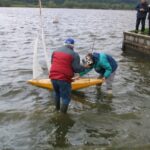 Bevor das Boot ganz im Wasser ist steigt Neptun schon in die Stiefel des Skippers: Wenn man aber auch den Taufsekt für die KAMPHAAN vergisst!